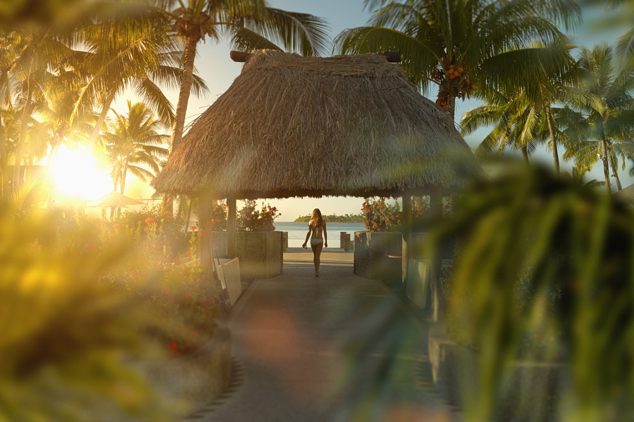 Caucasian girl walking under hut in tropical beach